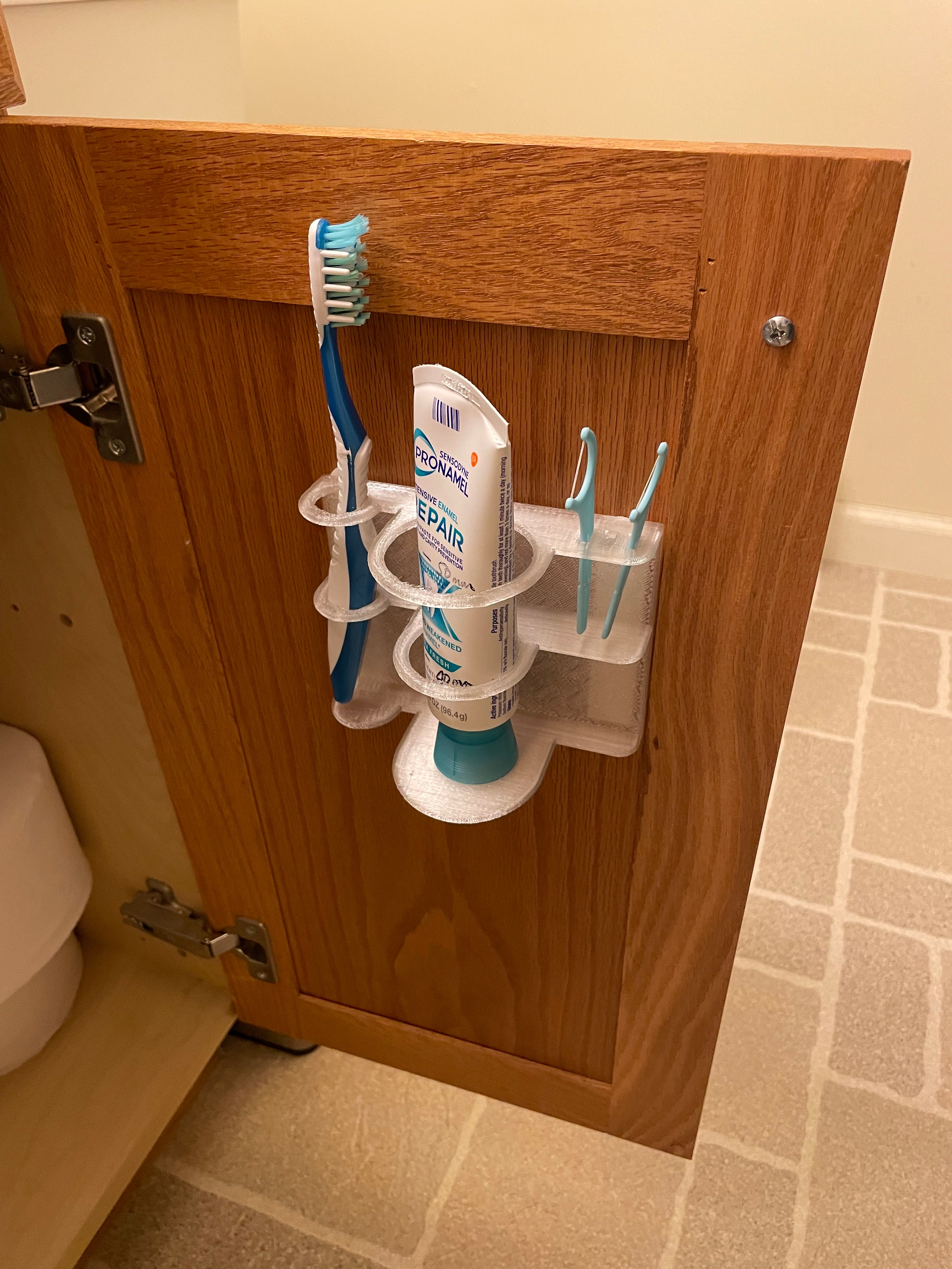 Wall-mounted toothbrush holder with space for toothpaste and dental floss